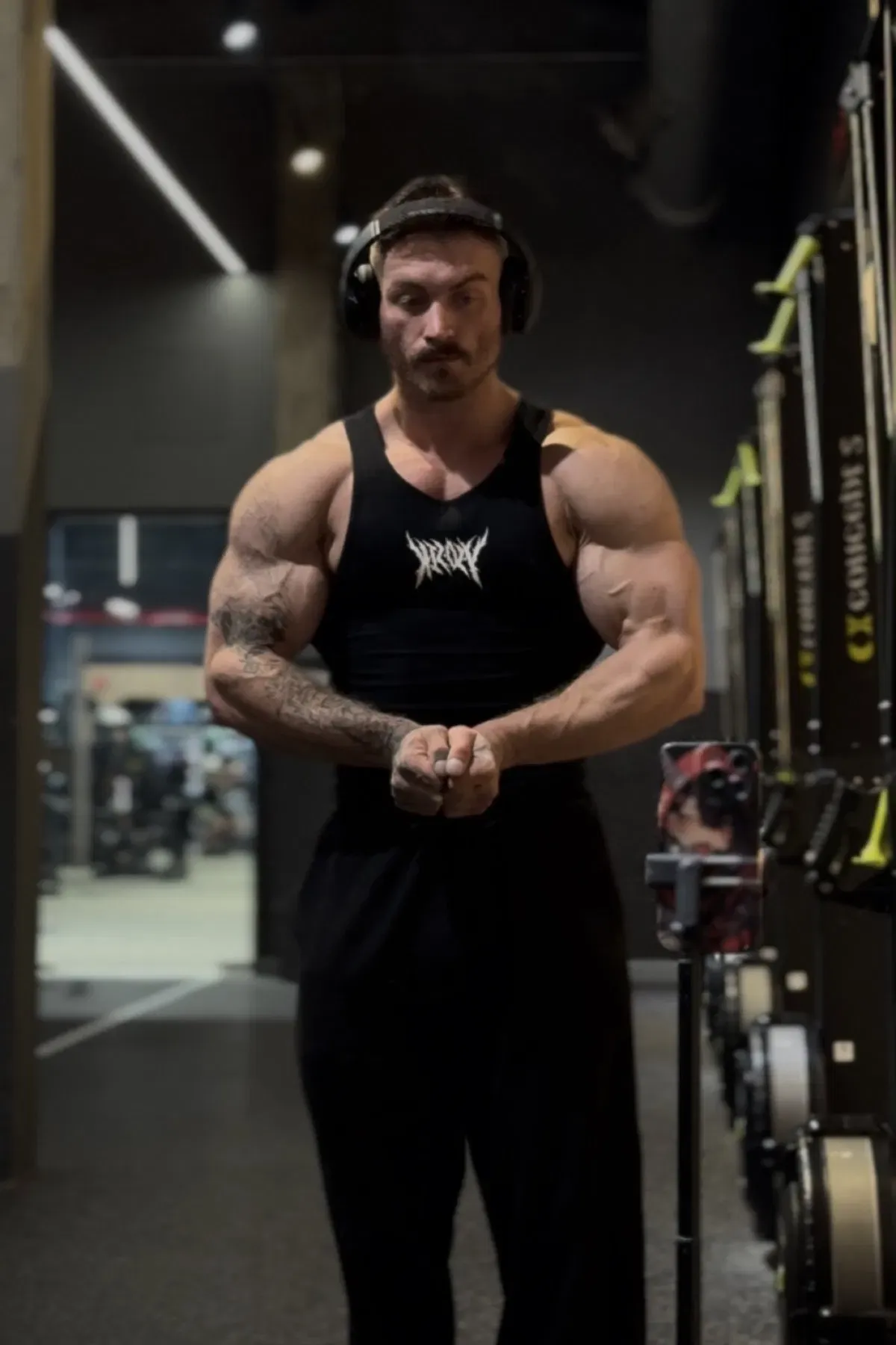 Focused athlete wearing headphones and posing in a gym, surrounded by strength equipment