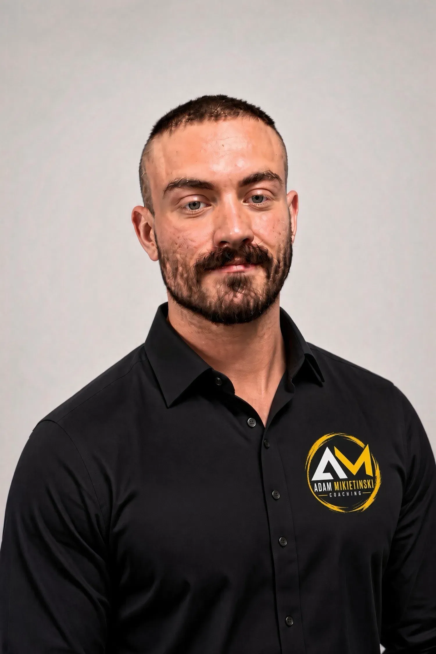 Adam Mikietinski in a black AM Coaching shirt, looking toward the camera
