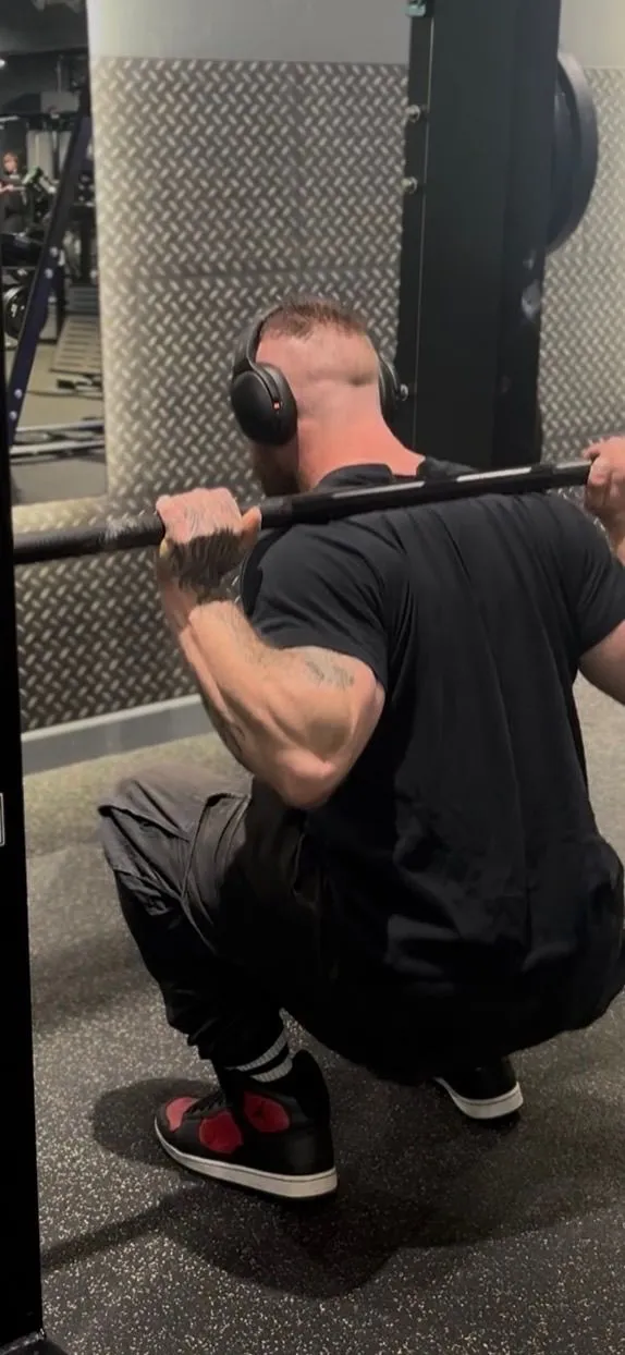 Athlete performing a controlled barbell squat in a gym